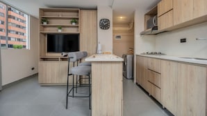 A modern kitchen with wooden cabinets, a built-in TV, and a bar stool. - 7th floor modern apartment close to parque lleras (Medellín)
