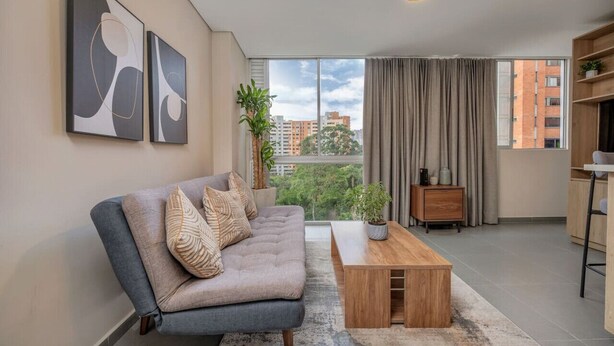 A modern living room with a sofa, a coffee table, and artwork on the wall. - 7th floor modern apartment close to parque lleras (Medellín)
