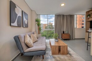 A modern living room with a sofa, a coffee table, and artwork on the wall. - 7th floor modern apartment close to parque lleras (Medellín)
