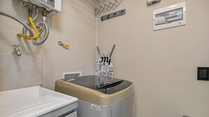 A compact laundry room with a washing machine, a sink, and a hose system.