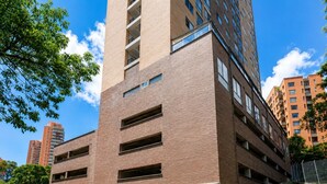 A multi-story parking garage with a brick facade, multiple levels of parking, and a gated entrance. - 24th floor modern apartment close to parque lleras (Medellín)