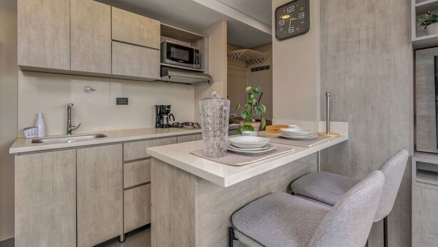 A modern kitchen with a microwave, sink, and a clock on the wall.