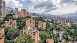 Une zone urbaine densément peuplée, avec de grands immeubles d’habitation, entourée de verdure et dominée par des montagnes en arrière-plan.