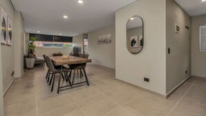 Un comedor espacioso con una mesa y sillas de madera, un espejo grande en la pared y una planta en maceta.