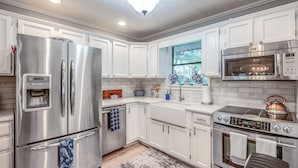 Una cucina moderna con elettrodomestici in acciaio inossidabile, mobili bianchi e un tappeto decorato.