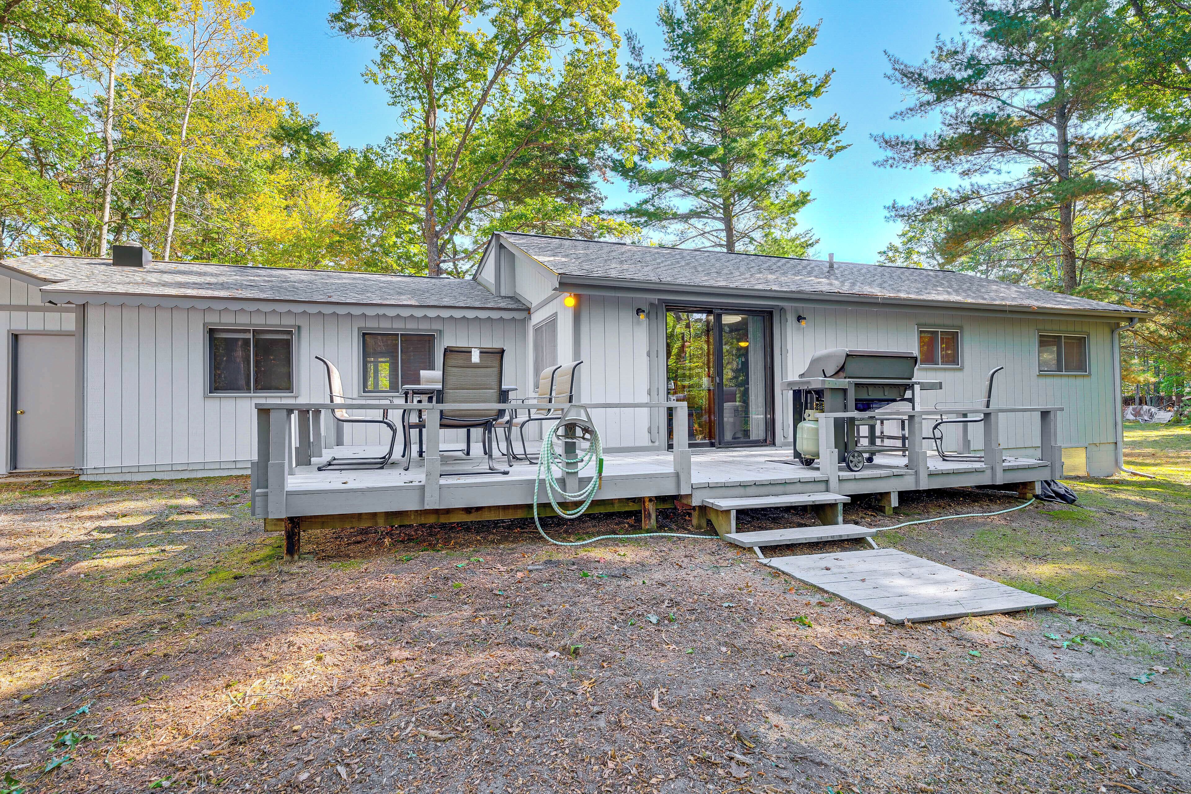 A two-story cabin with a deck, outdoor seating, and a grill area.