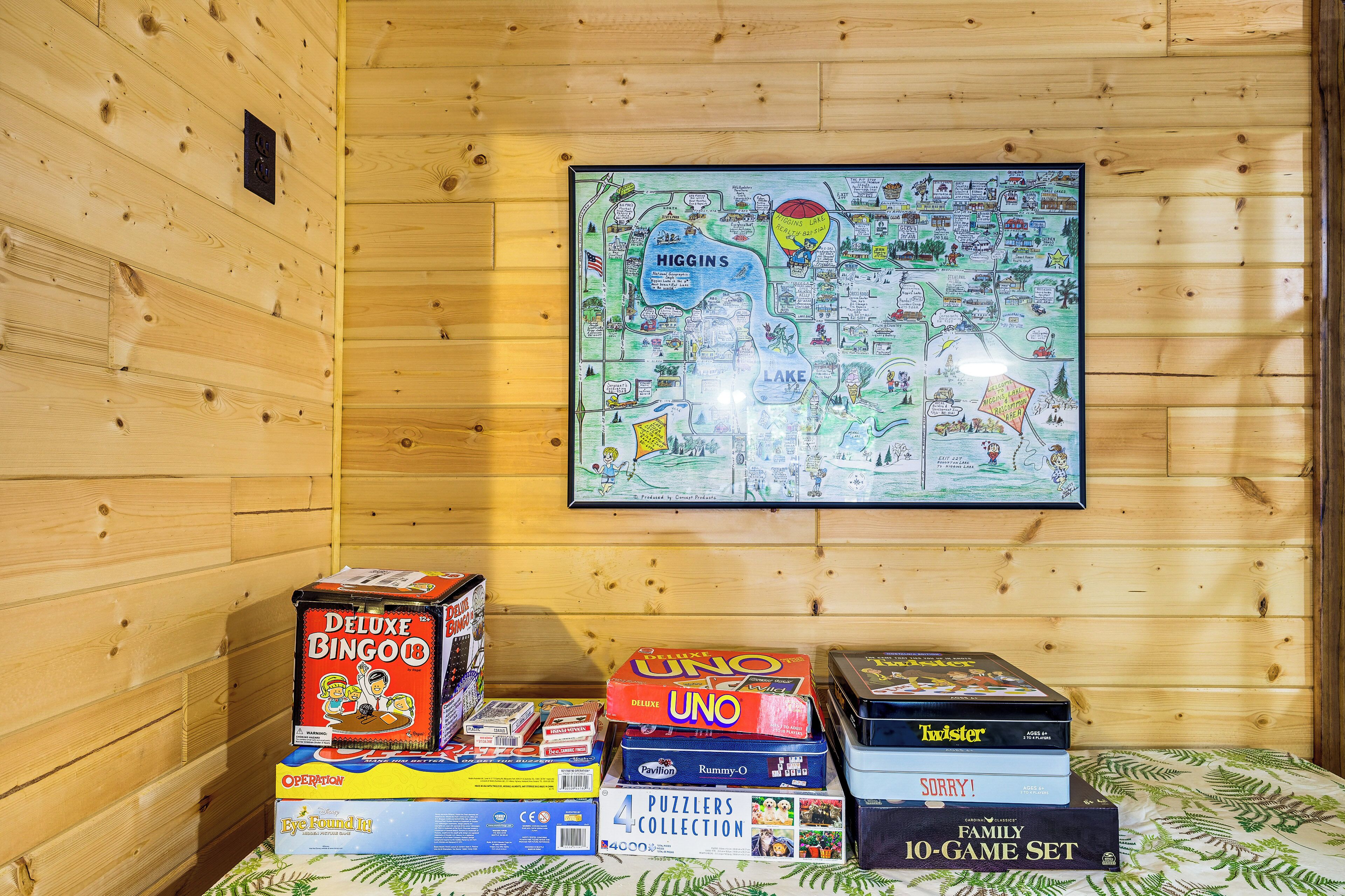 A wooden cabin interior with a map on the wall and a variety of board games on a table.