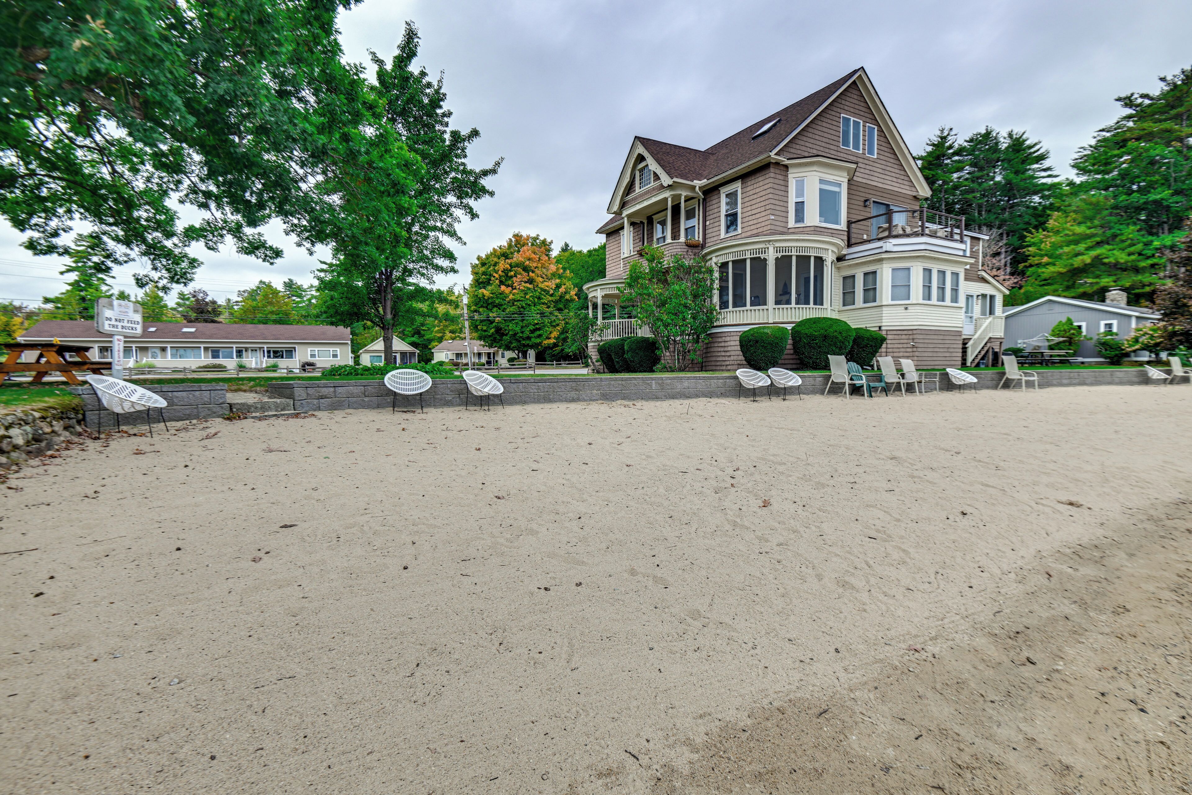A large house with a porch and a sandy beach in front.