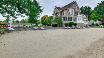 A large house with a porch and a sandy beach in front.