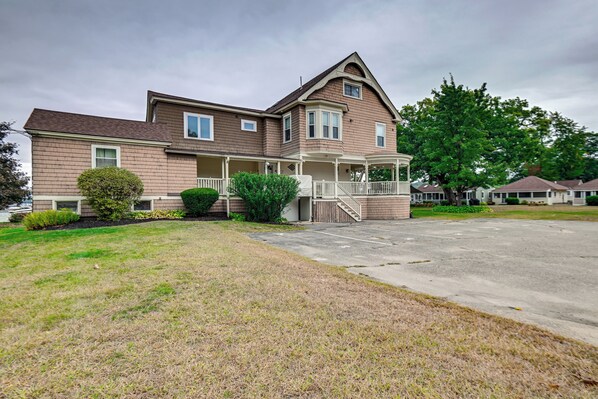 A two-story house with a front porch, a driveway, and a well-maintained lawn. - Lake Winnipesaukee Condo w/ Beach Access! (Gilford)