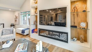 A modern living room with a fireplace, built-in shelves, and a cozy seating area. - Lake Winnipesaukee Condo w/ Beach Access! (Gilford)