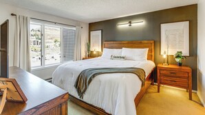 Ein ordentlich eingerichtetes Schlafzimmer mit einem großen Bett, Nachttischen und einem Blick durch das Fenster.