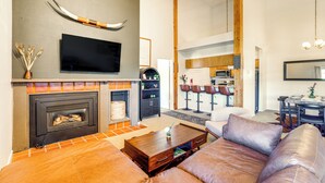 Ein modernes Wohnzimmer mit Kamin, Ledersofas, einem Flachbildfernseher und einer Essecke mit Barhocker.
