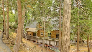 A log cabin with a wooden deck and a staircase leading to the porch.