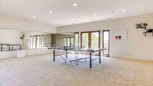 En rummelig stue med et pingpongbord, et stort spejl og en dør til en balkon.