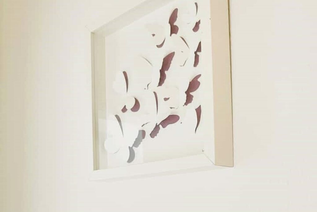 A framed abstract artwork on a plain wall.