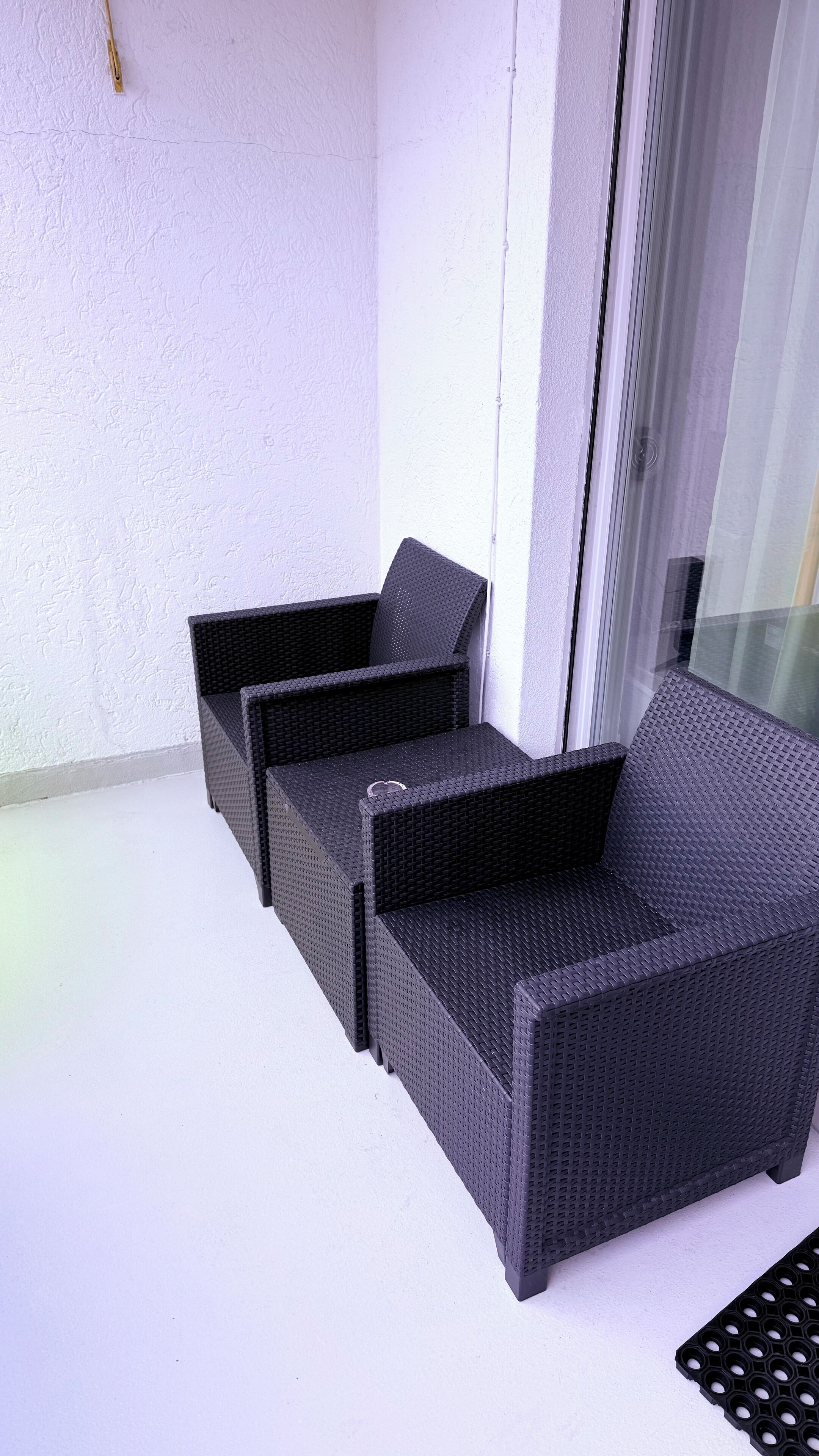Un balcone con due poltrone in vimini e un tavolino.