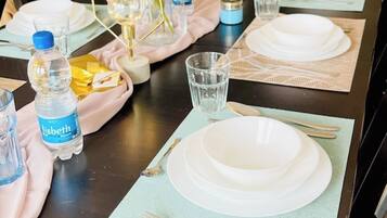 A table set with white plates, cutlery, and a water bottle.