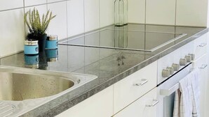 Une cuisine moderne dotée d’un plan de travail en granit, d’un évier en acier inoxydable et de meubles blancs.