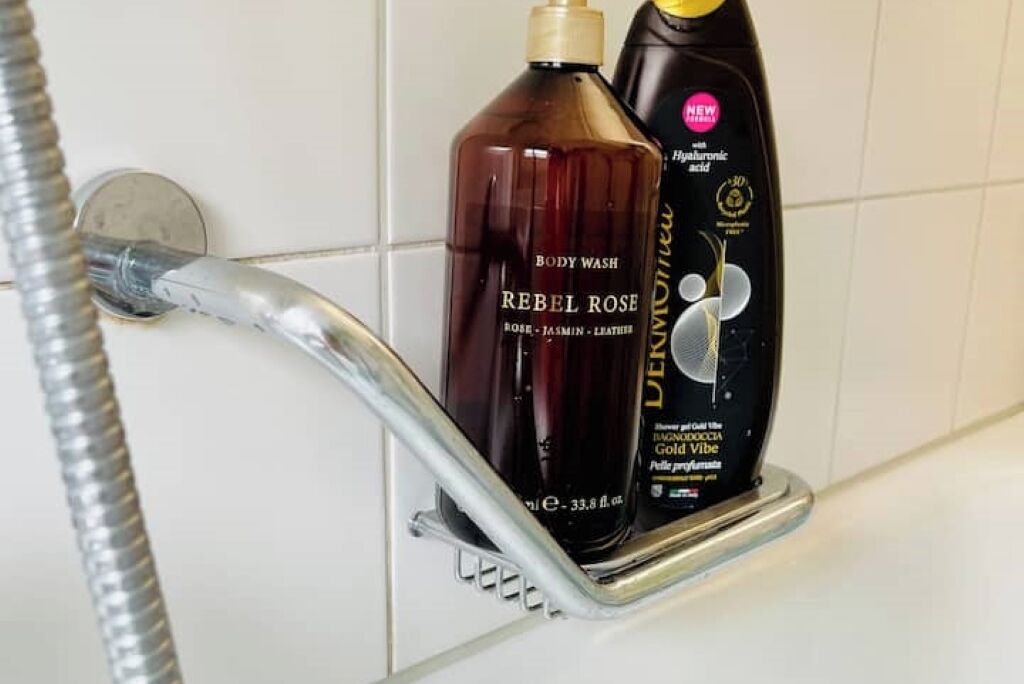 Une salle de bain équipée d’une douche, d’un flacon de gel douche Rebel Rose et d’un flacon de gel douche Dove.