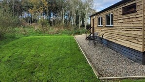 Eine Holzhütte mit Kiesterrasse und einer kleinen Sitzgruppe im Freien.