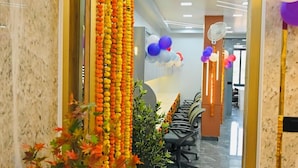 A reception area with a marble floor, a large potted plant, and a wall decorated with hanging ornaments.
