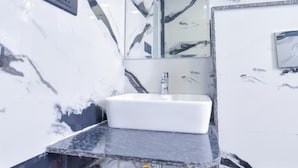 A bathroom with a white sink, marble-patterned walls, and a mirror.