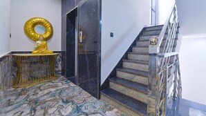 A marble-floored lobby with a golden statue, a staircase with metal railings, and a modern interior design.