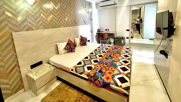 A modern bedroom with a large bed, a desk, and a TV.