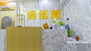 A reception area with a marble wall, a reception desk, and decorative golden geometric wall art.
