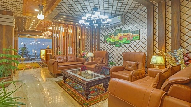 A spacious living room with leather sofas, a glass coffee table, and a chandelier.