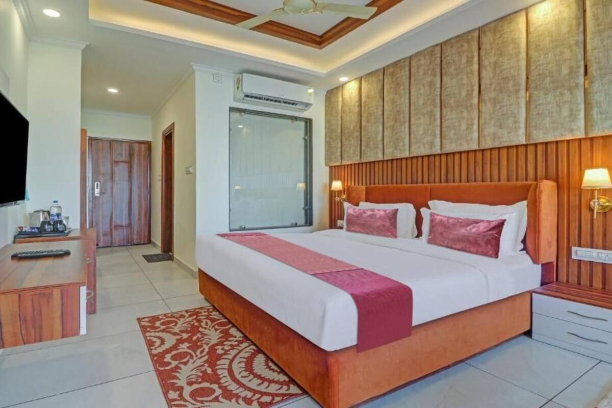 A hotel room with a large bed, a desk with a television, and a wooden headboard.