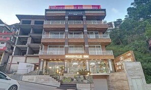 A multi-story building with the sign "WOODVILLE INN" on the facade. - Hotel Woodville Inn - Hotel in Mcleodganj  (Dharamshala)