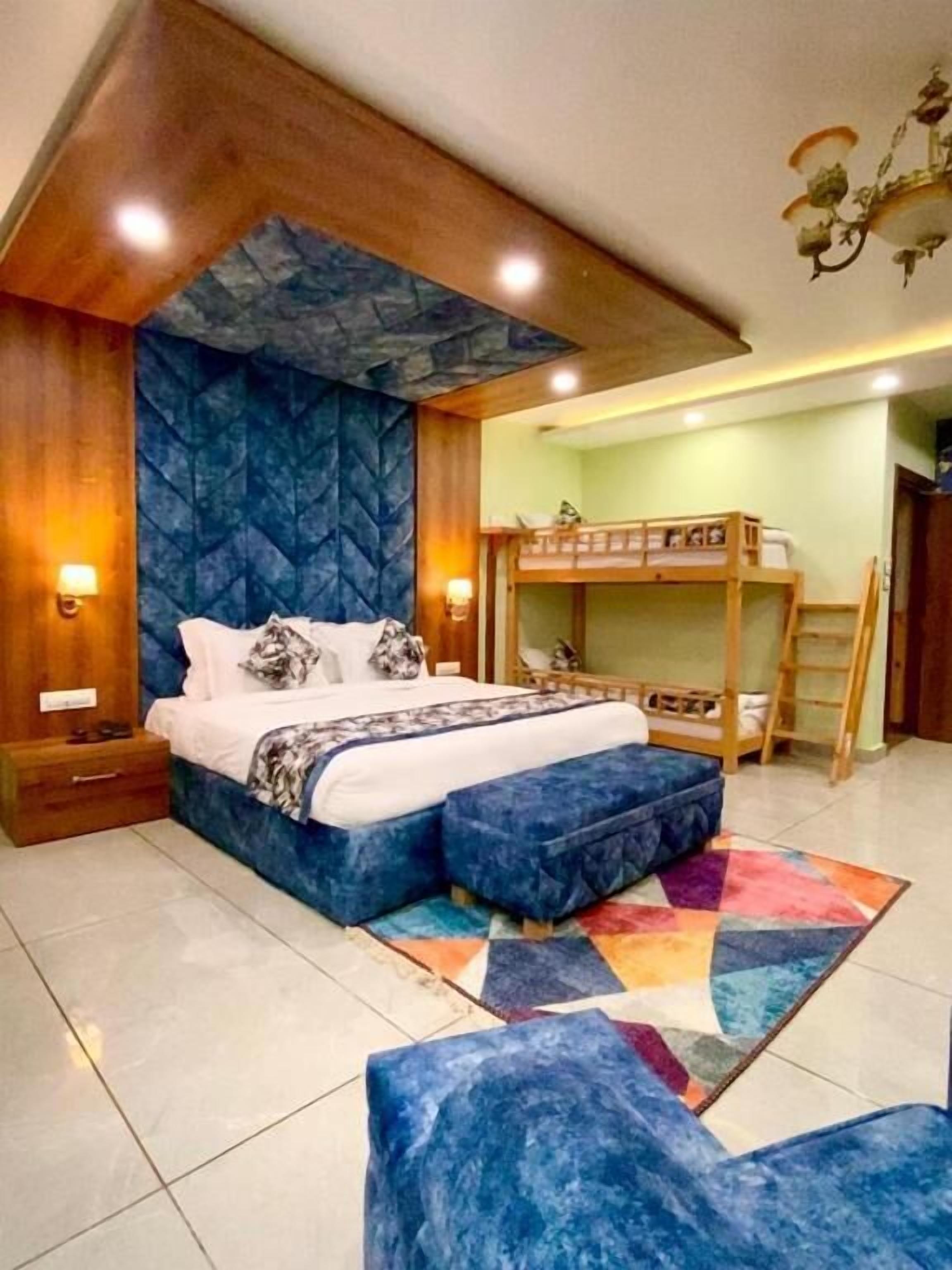 A bedroom with a bunk bed, a bedside table, a nightstand, a patterned rug, and a chandelier.