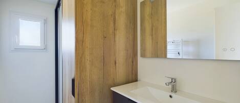 A modern bathroom with a wooden accent wall, a white sink, and a mirror above it.