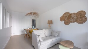 A modern living room with a white sofa, a small round table, and a lamp.