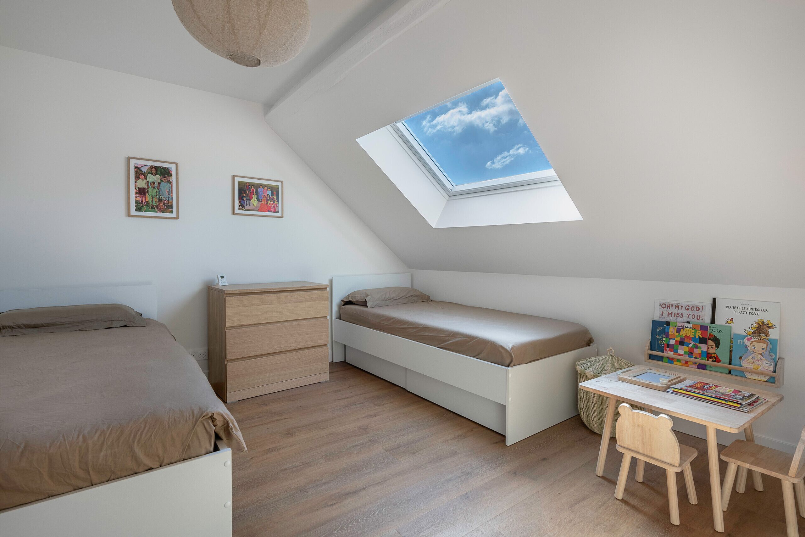 Un dormitorio con cama en alto, un escritorio y tragaluces.