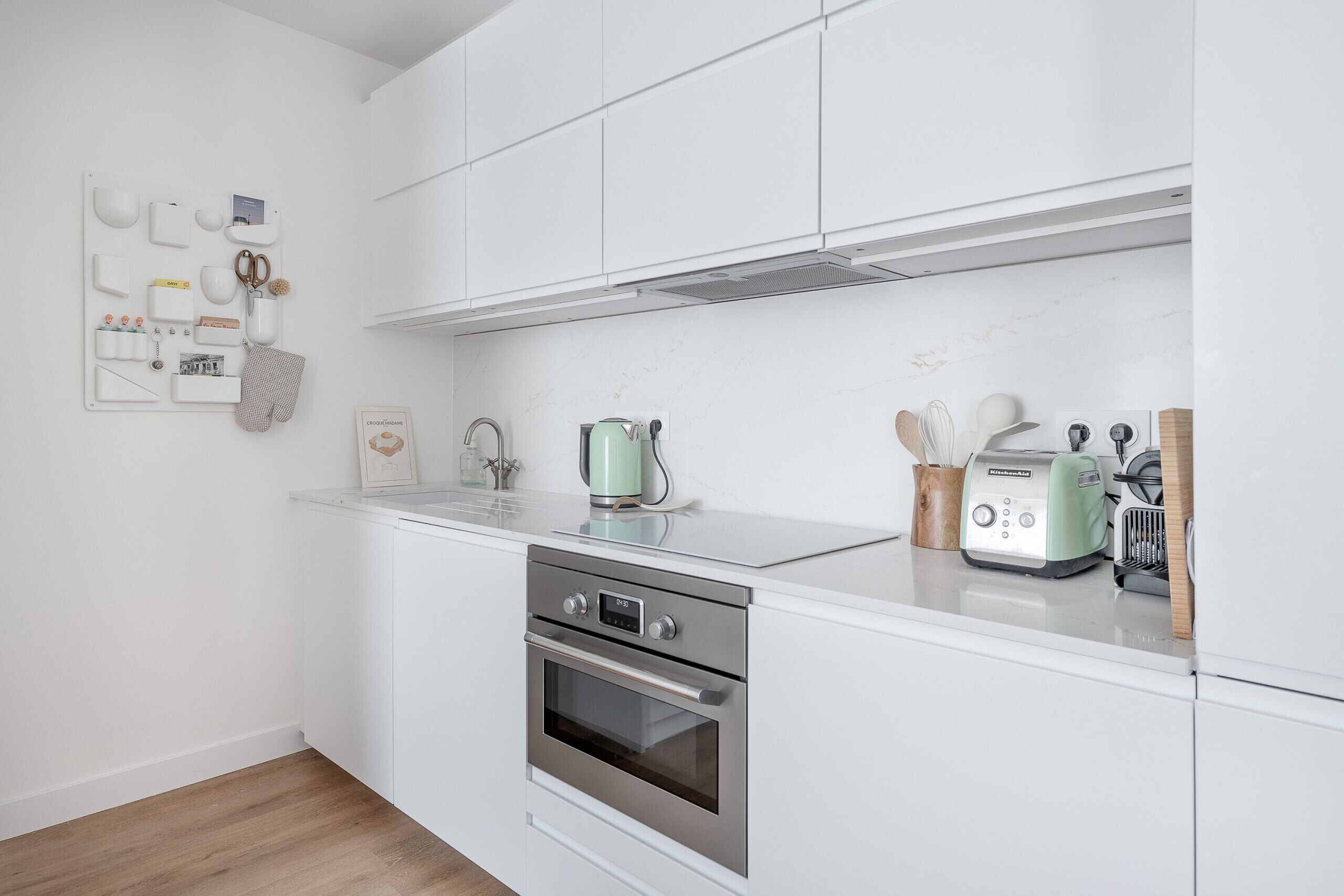 A modern kitchen with white cabinets, stainless steel appliances, and a marble countertop.