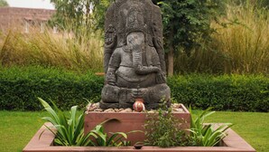 A stone statue of a seated figure in a garden setting. - Narsingh Bagh Resort (Bari)