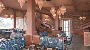 A restaurant with patterned blue booths, hanging ornate light fixtures, and a stone staircase. - Narsingh Bagh Resort (Bari)