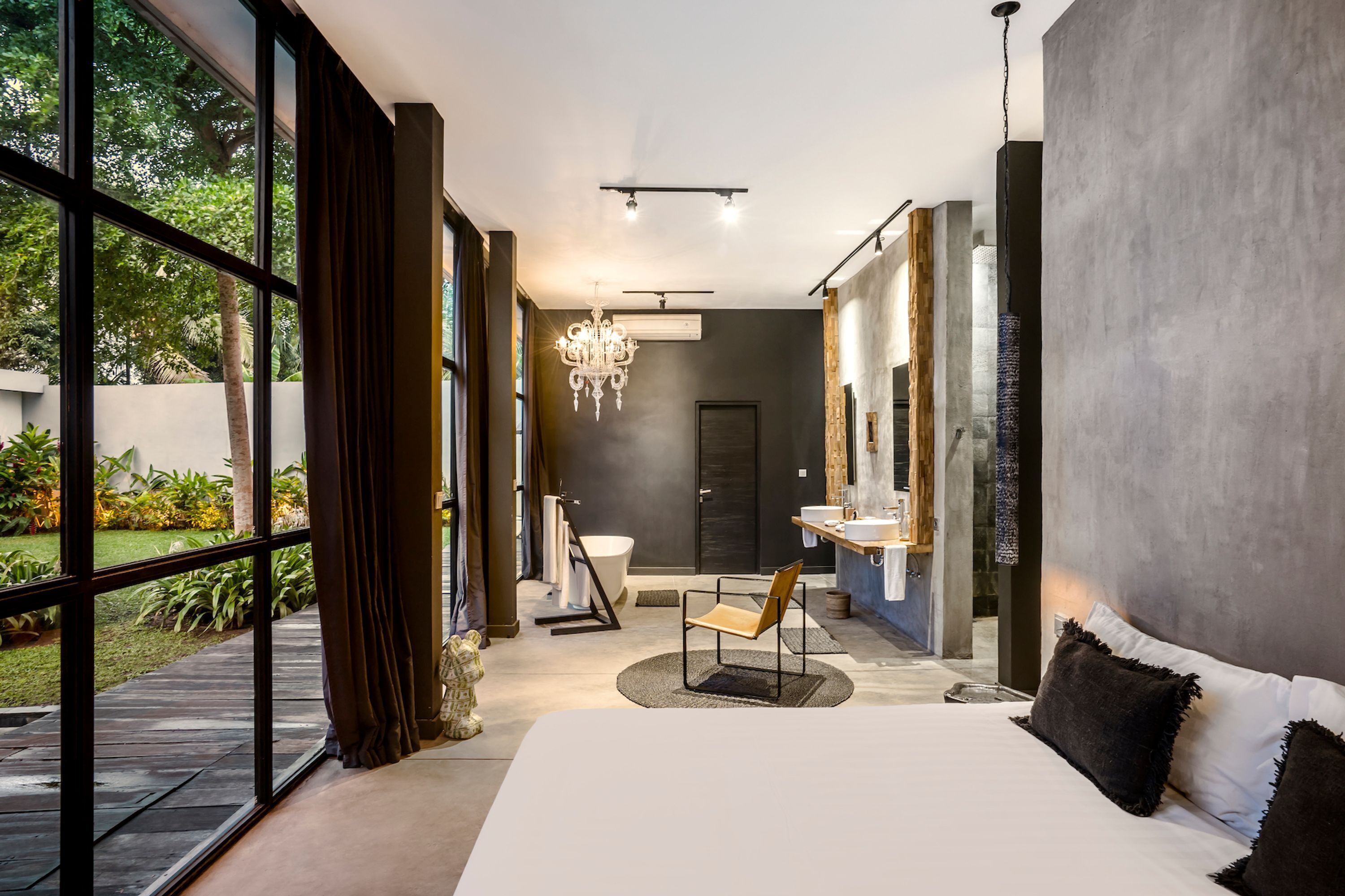 A modern bedroom with a large bed, a desk, and a bathroom visible through an open door.