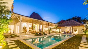 A well-lit outdoor pool area with a clear pool, surrounded by a grassy lawn and stone steps. - Villa M by Alfred in Bali - Stunning Family Villa With Pool at Seminyak Beach (Seminyak)