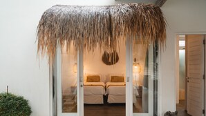 A room with a thatched roof entrance, two beds with pillows, a hanging light fixture, and a small decorative bird sculpture. - Villa M by Alfred in Bali - Stunning Family Villa With Pool at Seminyak Beach (Seminyak)