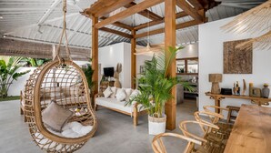 Une pièce spacieuse avec un fauteuil suspendu, des meubles en bois et des plantes en pot.