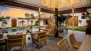 A spacious outdoor area with a pool, wicker furniture, and a thatched-roof structure. - Villa Folie by Alfred in Bali - New 5bdr Dream Villa in the Heart of Seminyak (Seminyak)