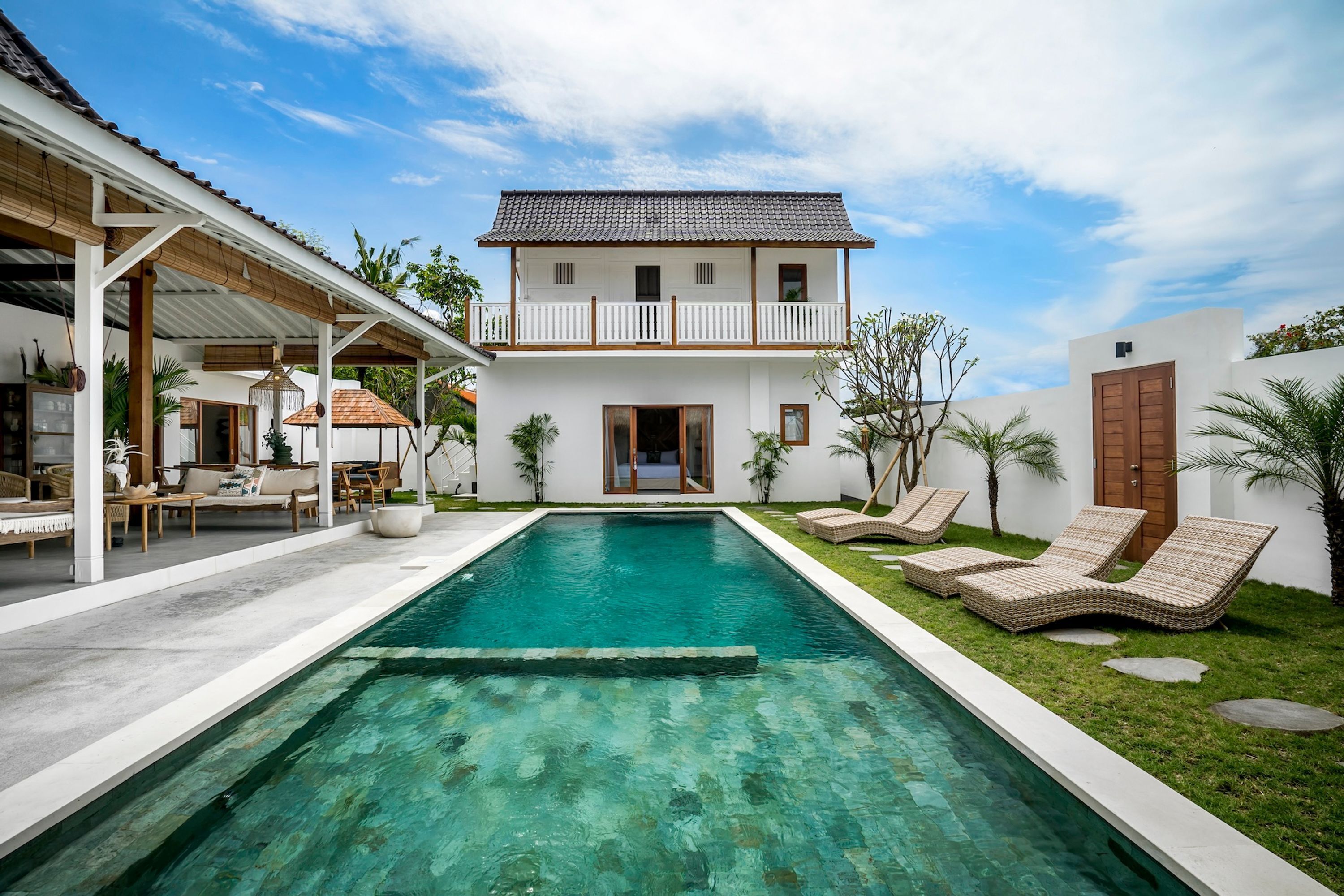 A two-story house with a swimming pool, outdoor seating, and a covered patio area.