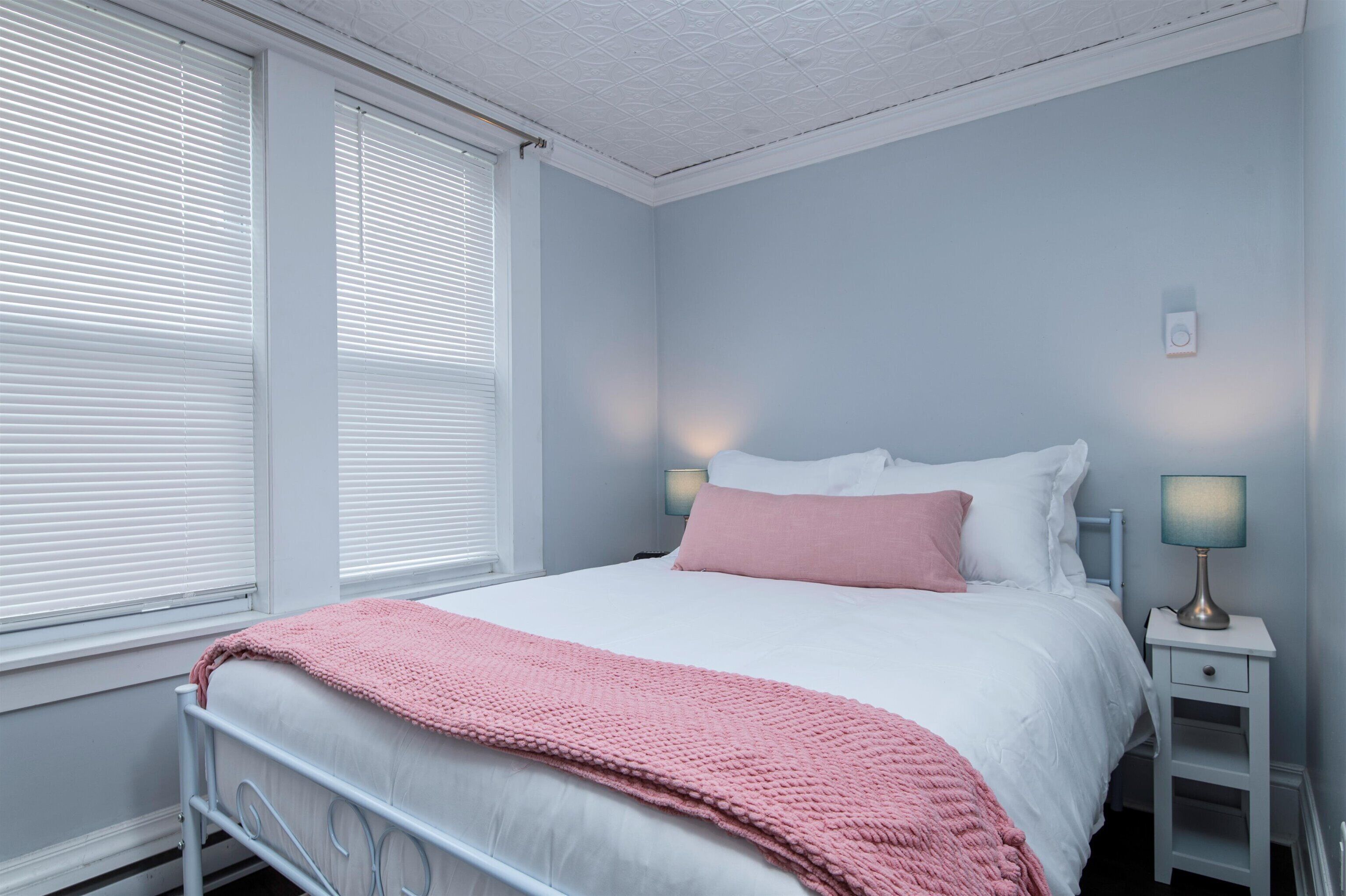A bedroom with a bed, bedside tables, and a window with blinds.