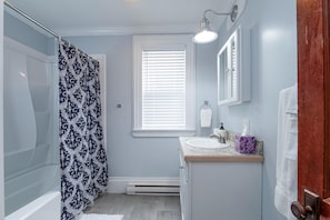 A bathroom with a shower, a sink, a window with blinds, and a towel rack. - Fully Stocked Kitchen,  AC,  Wi-Fi, W/D,  Near Baseball and Walk to Downtown (Oneonta)
