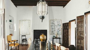 Un comedor con una mesa larga, sillas, un candelabro, obras de arte y una chimenea.