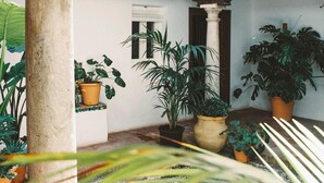Un patio con una columna de piedra, plantas en macetas y un balcón de madera.